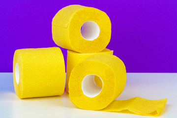 Minimalistic composition of bright yellow toilet paper rolls on purple background