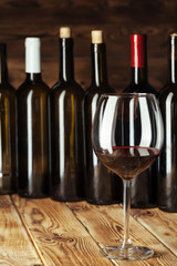 Wine bottles with glass, wooden background