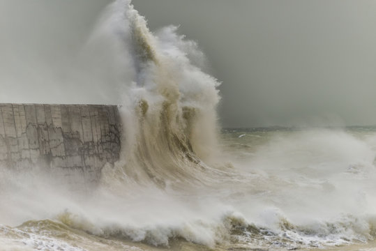 Stunning dangerous high waves crashing over harbor wall during windy Winter storm at Newhaven on English coast