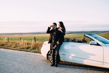 Sympathetic couple husband and wife spend time outside the city, sitting on a car hood