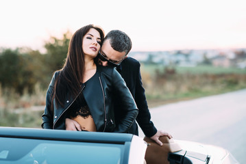 Sympathetic couple husband and wife spend time outside the city and sit in a car cabriolet in the...