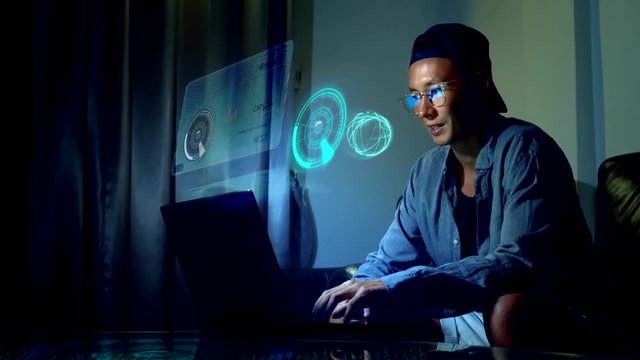 Futuristic network concept. Technology. Digitization of information flows. 5g or 4g internet speed. Young handsome asian man in glasses with reflections using his laptop, sitting in the evening in the