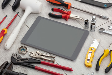 Tablet with empty screen and construction tools around 
