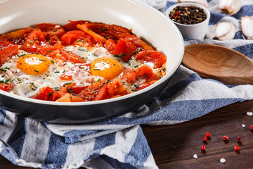 Shakshuka - fried eggs with vegetables in frying pan