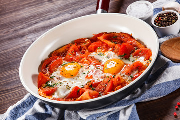 Shakshuka - fried eggs with vegetables in frying pan