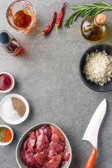 top view of raw meat, rice, spices, oil, cognac, peppers and knife