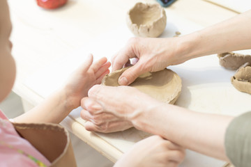 Children make clay. The hands of the child hold the clay. Light room. Clay dishes