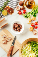 mushrooms on cutting board with cabbage and celery in plate with oil, cherry tomatoes, lime