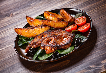 Grilled steak with potatoes and vegetables on wooden table