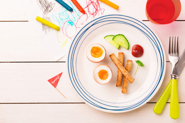 Kid's breakfast - eggs, toasts, cucumber and ketchup