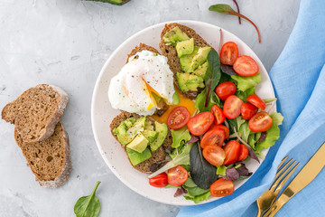 Healthy Breakfast with avocado toasts, poached egg and salad
