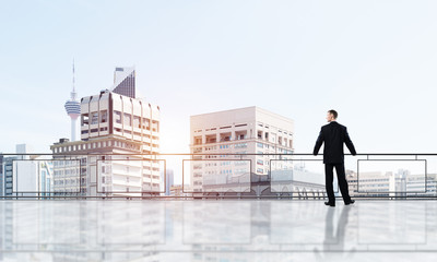 Sunrise above skyscrapers and businessman facing new day
