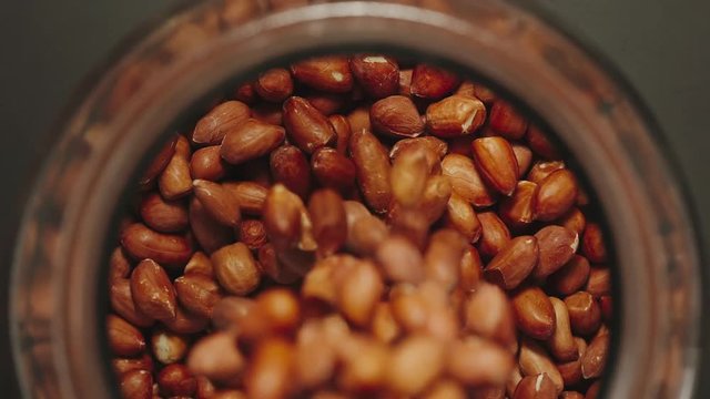 TOP VIEW: Peeled peanuts falling into a glass jar - Slow Motion