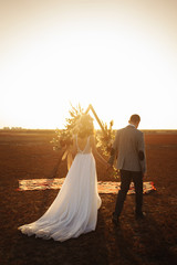 young and beautiful bride and groom enjoy each other. Wedding day in boho style. Sunshine portrait of happy bride and groom outdoor in nature at sunset. Warm summertime. © maxbelchenko