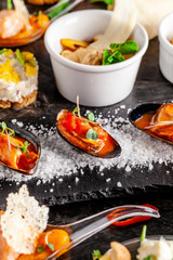 European cuisine. appetizer for wine on a black background. Pate, mini salad, canape, sea products, salmon and mussels in tomato sauce. Top view, copy space