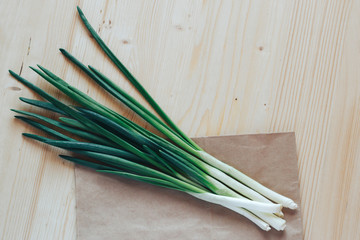 Fresh green onion on paper bag on wooden table.