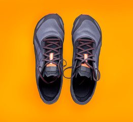 Top view of gray and orange trainers isolated on a orange background.