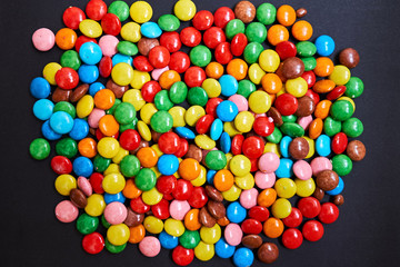 Fototapeta na wymiar Color small chocolate dragee. Candy on a black background. 