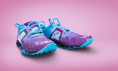 Front view of blue and purple trainers isolated on a pink background.