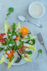 Chicorée Blutorangen Salat mit Soja Joghurt Dressing auf einem hellen Betonhintergrund