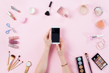 Make up products with woman holding smart phone.