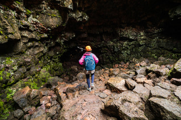 Woman traveler explore lava tunnel in Iceland.