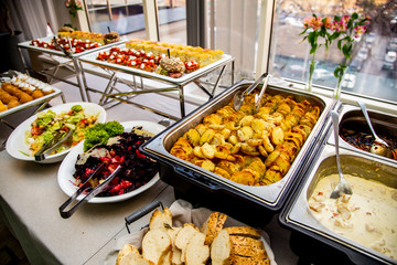  baked potato, chicken meat in sauce, fish, Vinigret, Caesar salad at catering event on some festive event, party or wedding reception