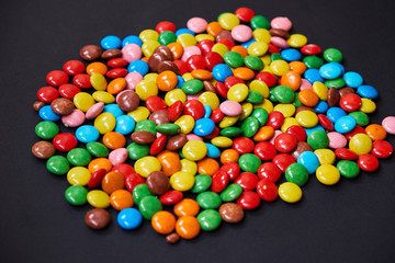 Color small chocolate dragee. Candy on a black background. 
