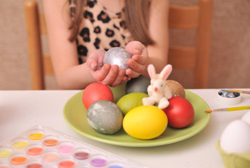 Fototapeta na wymiar Cute little girl painting easter eggs at home.