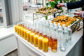 juices in glasses, mineral water on the table against the background of dishes  at catering event on some festive event, party or wedding reception