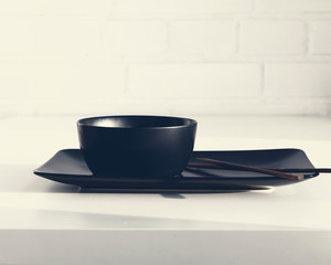 Japanese and asian cuisine concept. Black dishes and chopsticks.  Top view. White  brick wall background. Copy space.