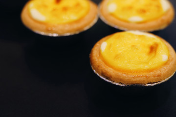 Fresh baked Hokkaido cheese tarts on a black background with copy space
