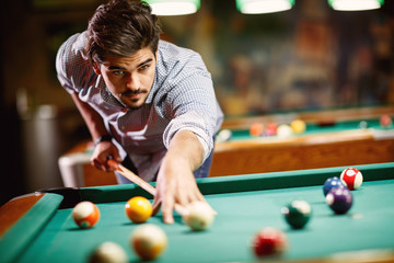 man aiming at pool ball to billiard game.