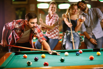 Young handsome man playing billiard game.