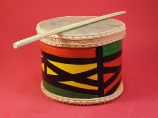Close-up of a colorful handmade Brazilian percussion instrument: a small drum with drumstick. It is...