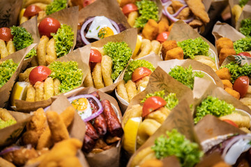 Crowded street fast food. Delicious snack cone with squid sausage quail egg rings of onion salad and tomato in city market for tourists.