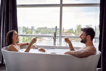 Sexy man and woman have fun together in the bathtub and drinking champagne.