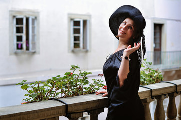 Attractive modern woman standing on the city street.Fashionable young woman walking in street in the city wearing shirt hat and jacket. Fashion summer photo,old city.