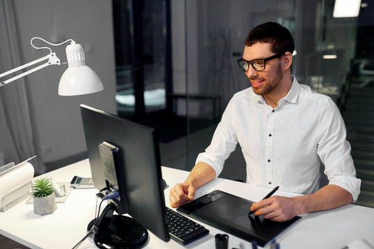 Business, Graphic Design And Technology Concept - Designer Or Businessman In Glasses With Computer And Pen Tablet Working At Dark Night Office