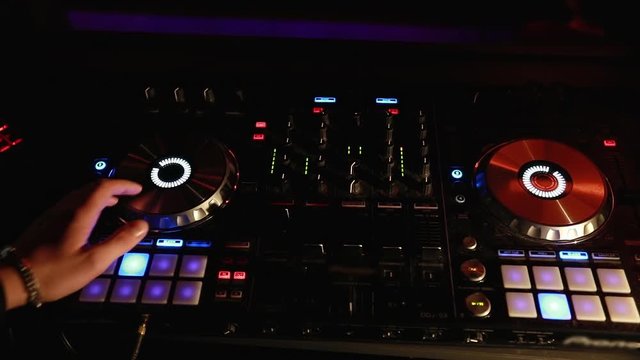 DJ turntable console mixer controlling with two hand in concert nightclub stage.