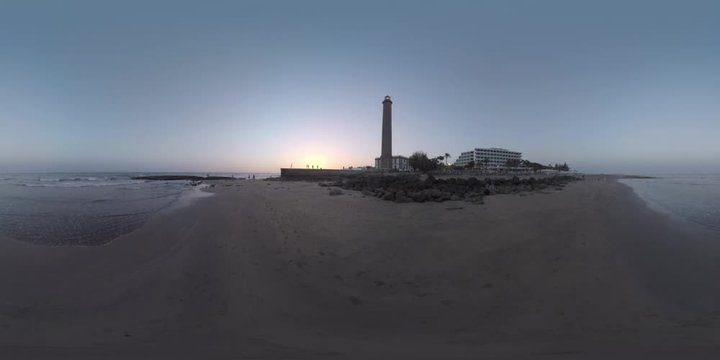 360 VR video. Waterscape, ocean coast with resort and people walking at the bottom of Maspalomas Lighthouse. Gran Canaria evening scene