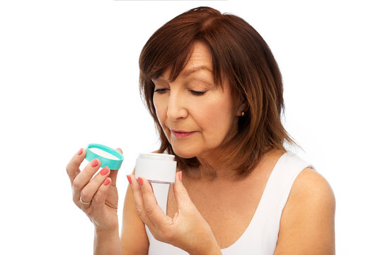 beauty, skincare and cosmetics concept - senior woman with cream jar