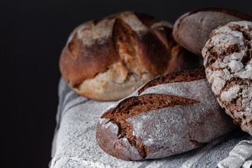 Loaves of traditional and natural bread on a wooden table with linen towel. Assortment of artisanal bread. Healthy food concept. Free space for input text.