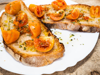 grilled bruschetta with Italian tomatoes, orange color, very good and lasting, seasoned with olive oil and oregano, for a healthy breakfast, lateral shot