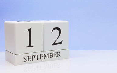 September 12st. Day 12 of month, daily calendar on white table with reflection, with light blue background. Autumn time, empty space for text