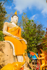 Yellow big Buddha on the stair way to the hill at Wat Khao Rup Chang or Temple of the Elephant Hill, one of the most famous attractions in Phichit province, Thailand. © kampwit