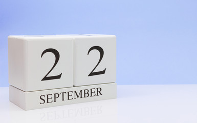 September 22st. Day 22 of month, daily calendar on white table with reflection, with light blue background. Autumn time, empty space for text