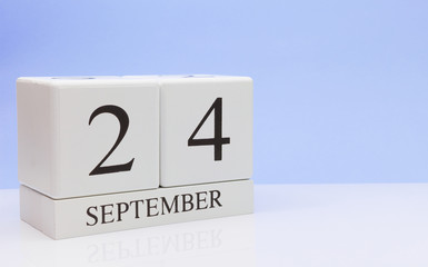 September 24st. Day 24 of month, daily calendar on white table with reflection, with light blue background. Autumn time, empty space for text