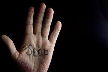Fototapeta premium The palm of an old grandmother with the word stop on a dark background
