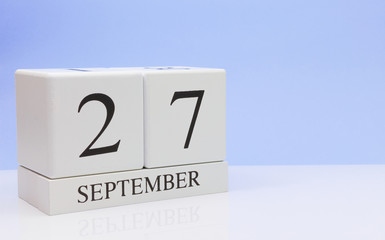 September 27st. Day 27 of month, daily calendar on white table with reflection, with light blue background. Autumn time, empty space for text